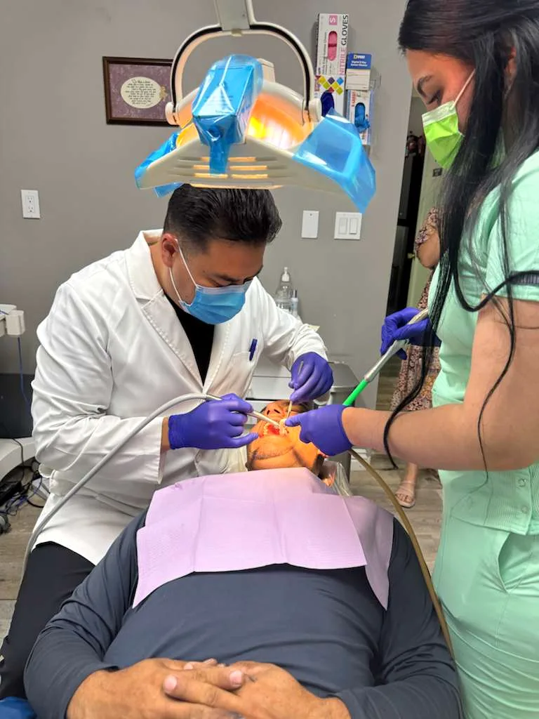 Dentista y asistente de Latino Americano Dental atendiendo a un paciente en San José